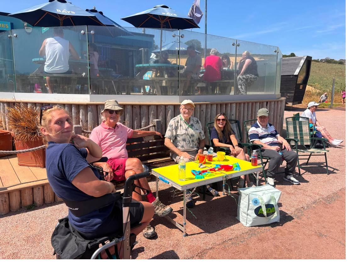 Guests and staff sitting in the sunshine outside the cafe at Broadsands beach