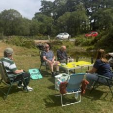 The group sitting out in camp chairs beside a Dartmoor stream